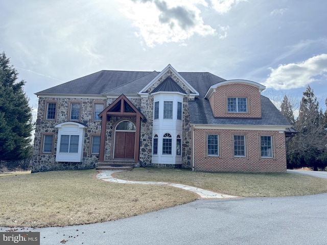 view of front facade featuring stone siding, brick siding, and a front yard