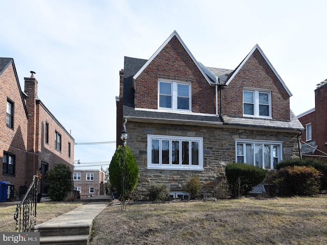 view of front of property with stone siding, brick siding, and a front lawn