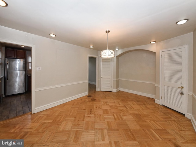 empty room featuring arched walkways, recessed lighting, and baseboards