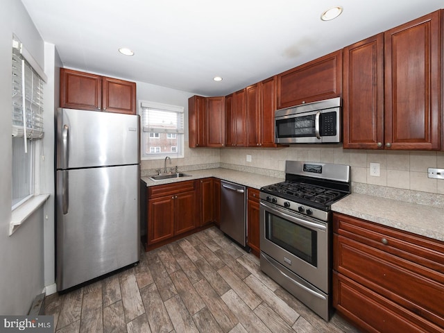 kitchen with tasteful backsplash, stainless steel appliances, a sink, and light countertops