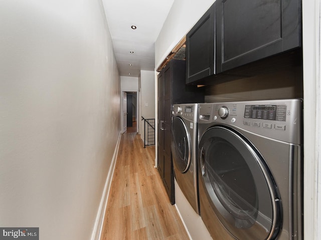 clothes washing area with light wood finished floors, separate washer and dryer, cabinet space, and baseboards