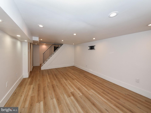 finished basement with light wood-style floors, baseboards, stairway, and recessed lighting