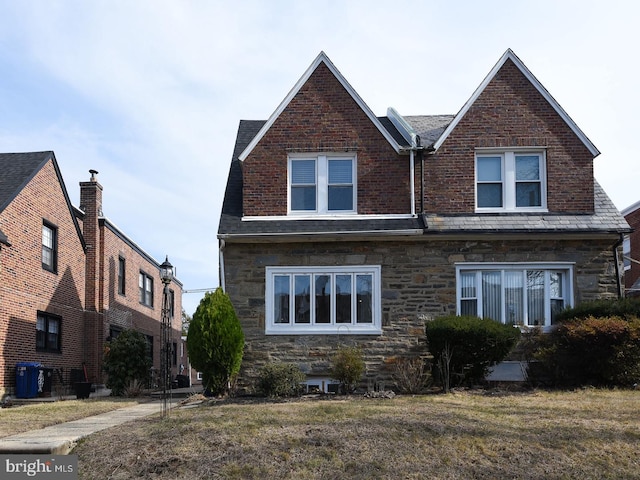 view of front of property featuring stone siding, a front lawn, and brick siding