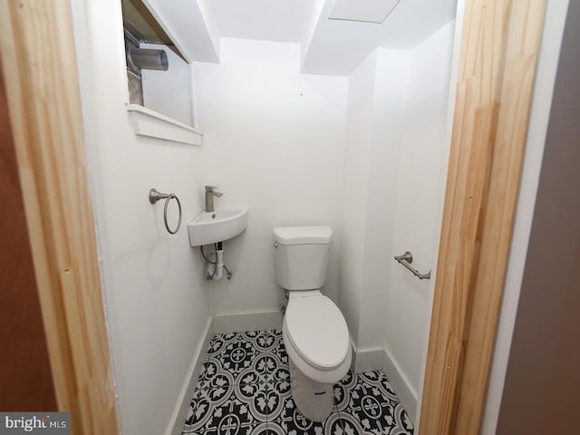 bathroom with baseboards, a sink, toilet, and tile patterned floors