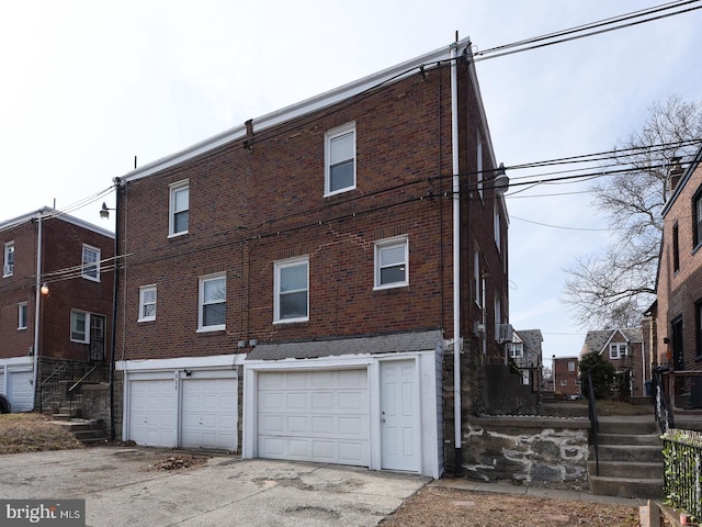 rear view of house with a garage, brick siding, and driveway