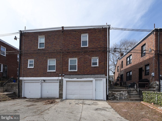 back of property with a garage and brick siding