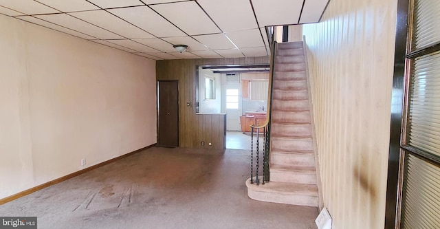 interior space featuring a paneled ceiling, concrete floors, and baseboards