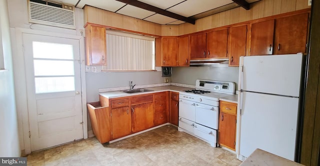 kitchen featuring white appliances, light floors, light countertops, under cabinet range hood, and a sink