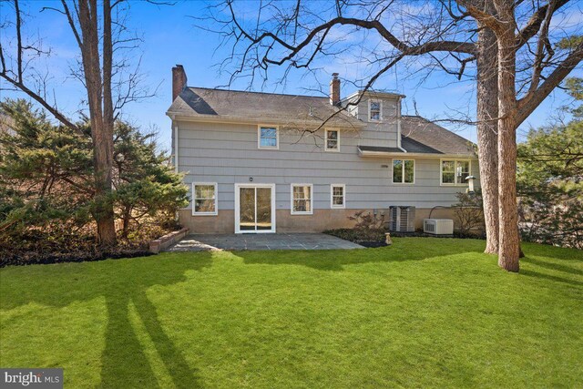 back of property with a lawn, a patio, a chimney, and central AC unit