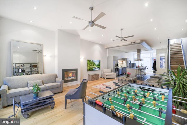 rec room with ceiling fan, a lit fireplace, light wood-type flooring, and recessed lighting