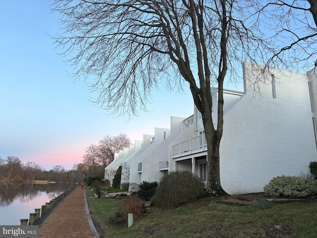 property exterior at dusk with a water view and stucco siding