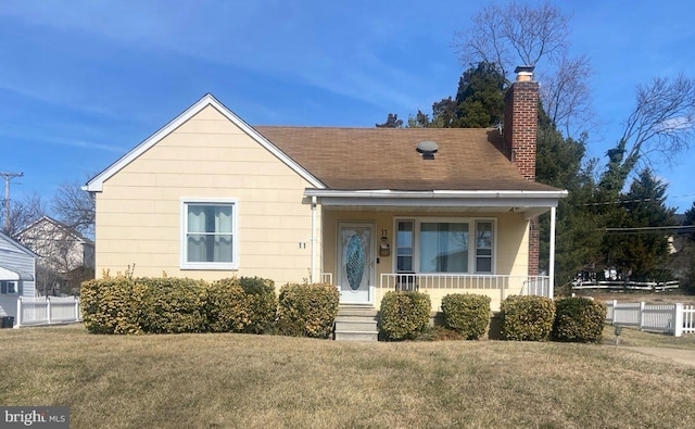 bungalow-style home with fence, roof with shingles, a porch, a chimney, and a front lawn