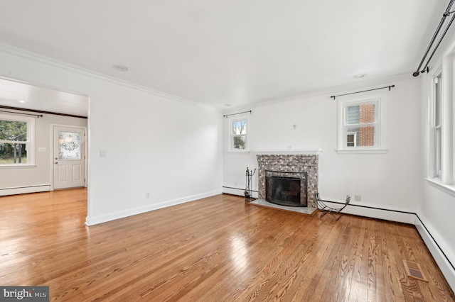 unfurnished living room featuring a stone fireplace, a baseboard heating unit, baseboards, light wood finished floors, and crown molding