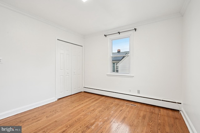 unfurnished bedroom featuring a baseboard radiator, wood finished floors, baseboards, a closet, and crown molding