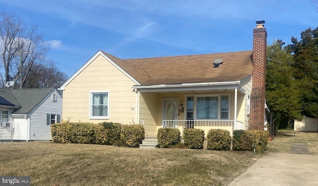 bungalow featuring roof with shingles, a chimney, a porch, and a front yard