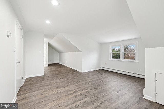 additional living space featuring a baseboard heating unit, baseboards, wood finished floors, and lofted ceiling