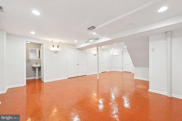 finished basement featuring visible vents, baseboards, a sink, and recessed lighting