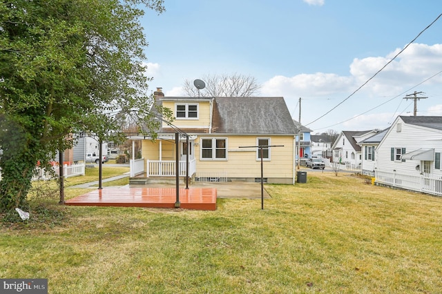 rear view of property with a chimney, a lawn, fence, a deck, and a residential view