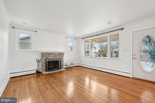 unfurnished living room featuring a baseboard heating unit, wood-type flooring, and crown molding