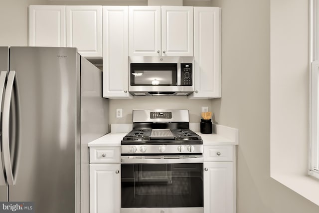 kitchen featuring stainless steel appliances, light countertops, and white cabinetry