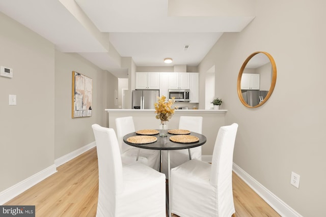 dining room featuring light wood-style floors, visible vents, and baseboards