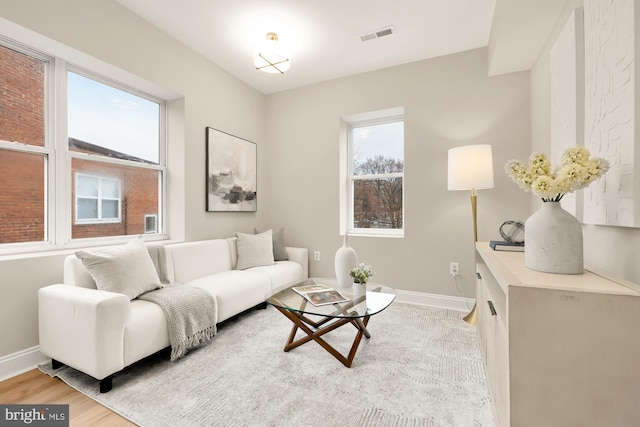 living area with light wood-type flooring, visible vents, and baseboards