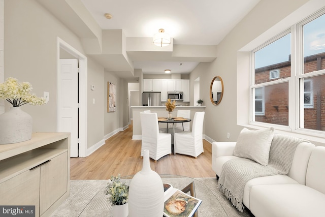 living area featuring baseboards and light wood finished floors