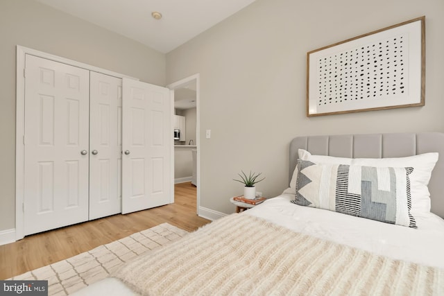 bedroom with a closet, wood finished floors, and baseboards