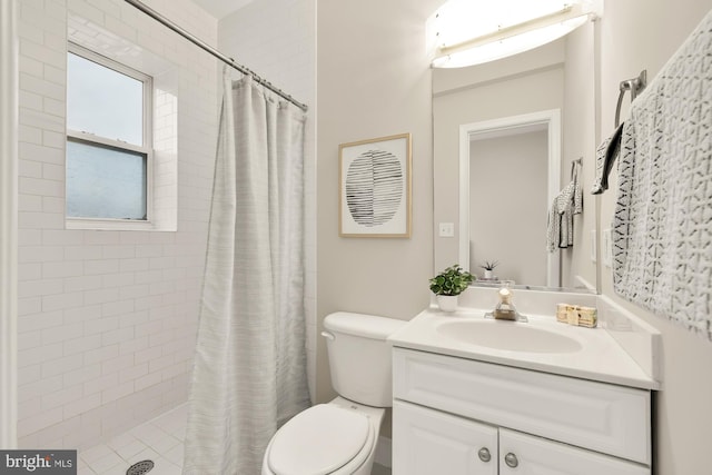 bathroom featuring a tile shower, vanity, and toilet