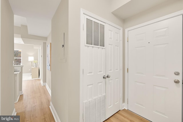 foyer entrance featuring light wood-style flooring, visible vents, and baseboards