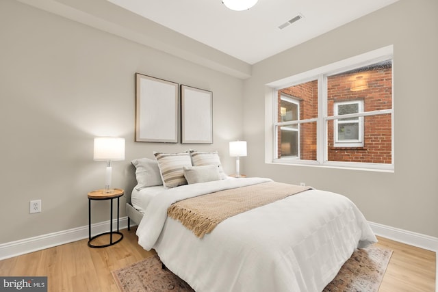 bedroom featuring light wood-type flooring, visible vents, and baseboards