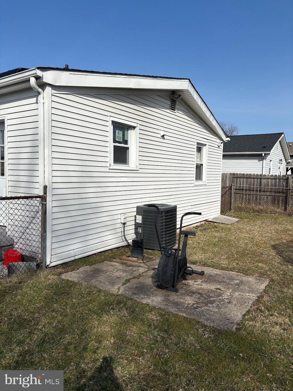 back of property featuring a yard, central AC, and fence