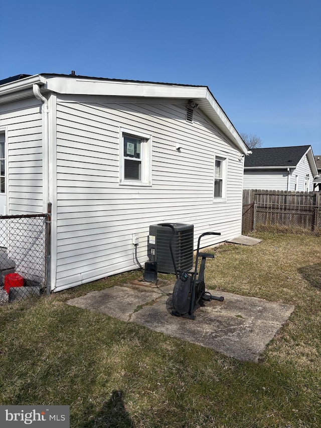 back of property featuring a yard, central AC, and fence