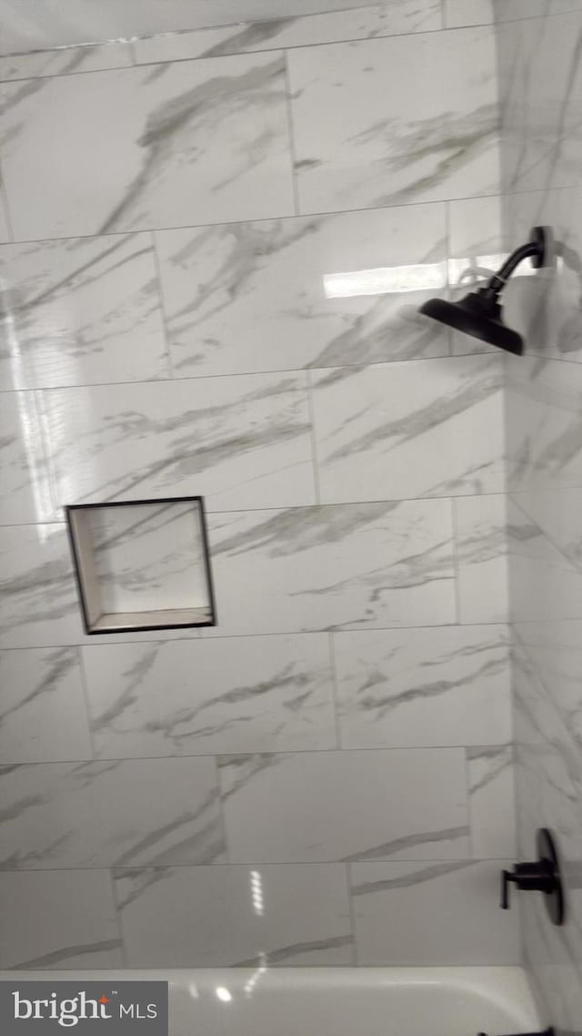 details with a combined bath / shower with marble appearance