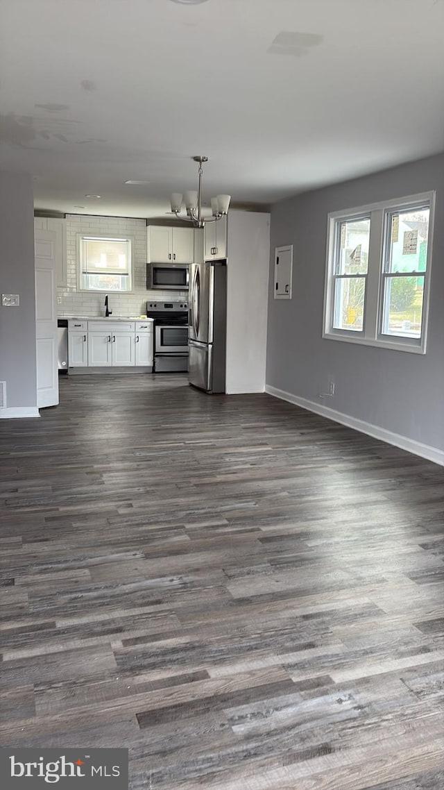 unfurnished living room with baseboards, a sink, and dark wood-type flooring