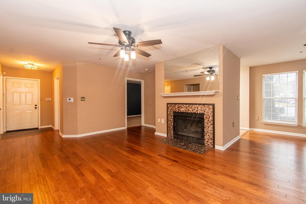 unfurnished living room featuring baseboards, wood finished floors, and a tile fireplace