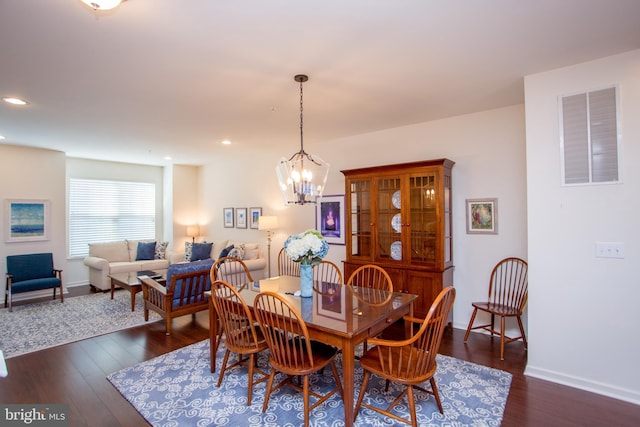 dining space with dark wood-type flooring, recessed lighting, visible vents, and an inviting chandelier