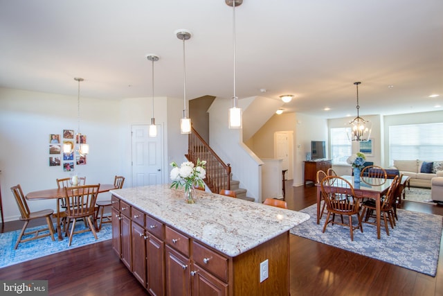 kitchen with open floor plan, light stone counters, dark wood finished floors, and a notable chandelier