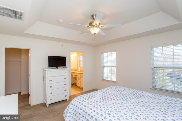 bedroom featuring a spacious closet, multiple windows, a raised ceiling, and visible vents