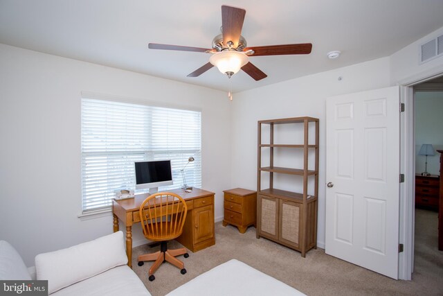 home office with light carpet, visible vents, and a ceiling fan