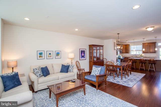 living area featuring recessed lighting, dark wood finished floors, and an inviting chandelier