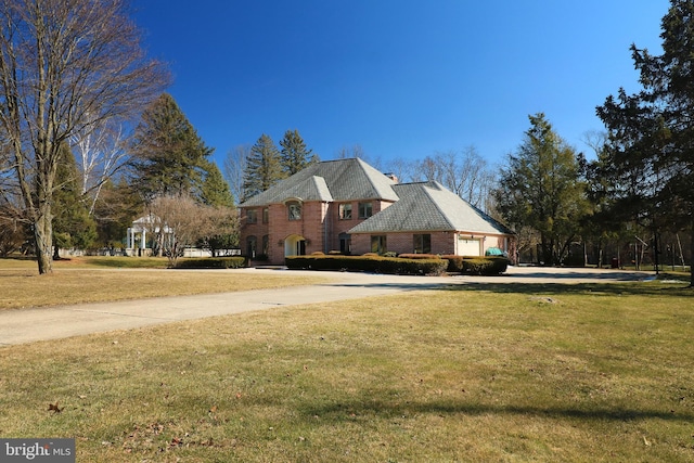 view of property exterior with an attached garage, a yard, concrete driveway, and brick siding