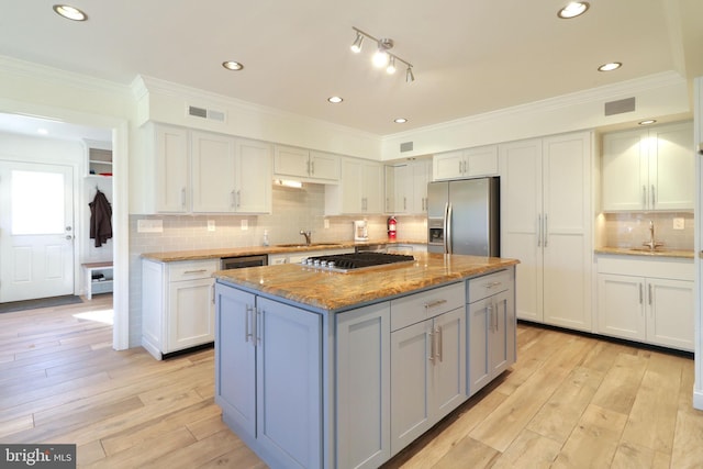 kitchen featuring visible vents, light wood-style flooring, a kitchen island, appliances with stainless steel finishes, and a sink