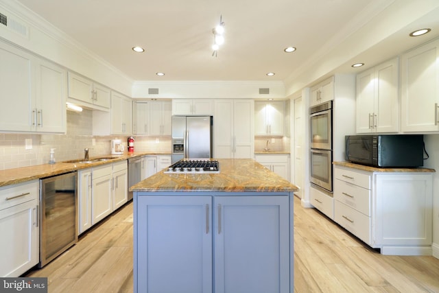 kitchen featuring beverage cooler, stainless steel appliances, a center island, visible vents, and light stone countertops