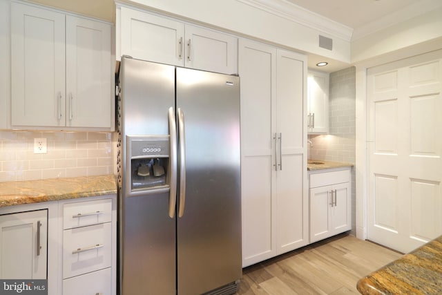 kitchen featuring stainless steel fridge, tasteful backsplash, light stone counters, crown molding, and light wood-style floors