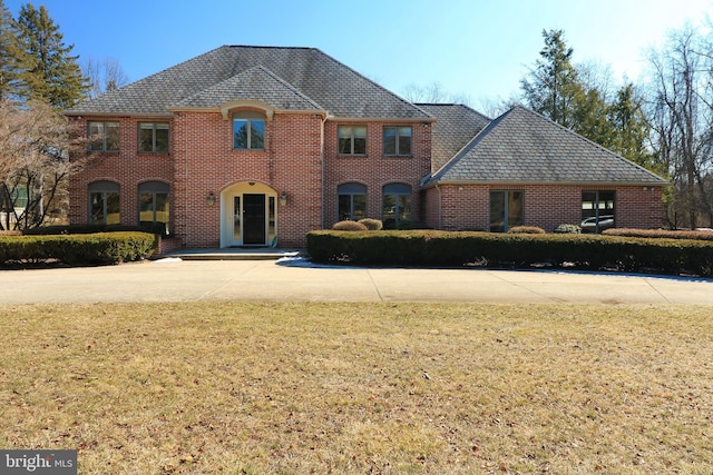 view of front of house with a high end roof, brick siding, and a front lawn