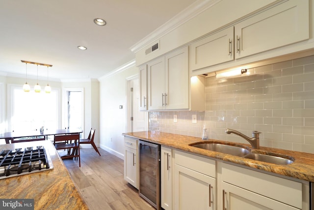 kitchen with wine cooler, crown molding, visible vents, stainless steel gas stovetop, and a sink