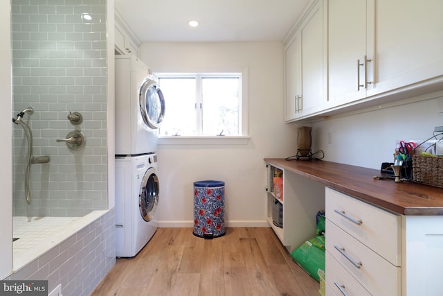 clothes washing area featuring stacked washer and clothes dryer, light wood finished floors, recessed lighting, laundry area, and baseboards