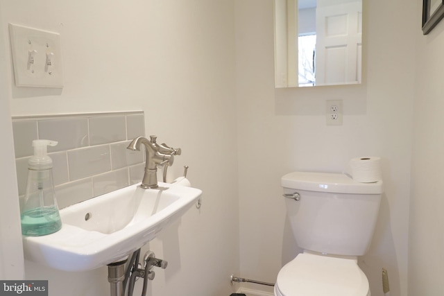 bathroom with a sink, toilet, and decorative backsplash