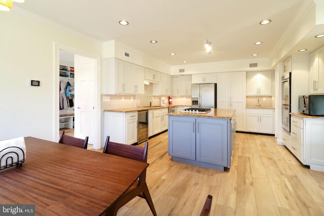 kitchen featuring white cabinets, appliances with stainless steel finishes, light wood-style flooring, and a center island